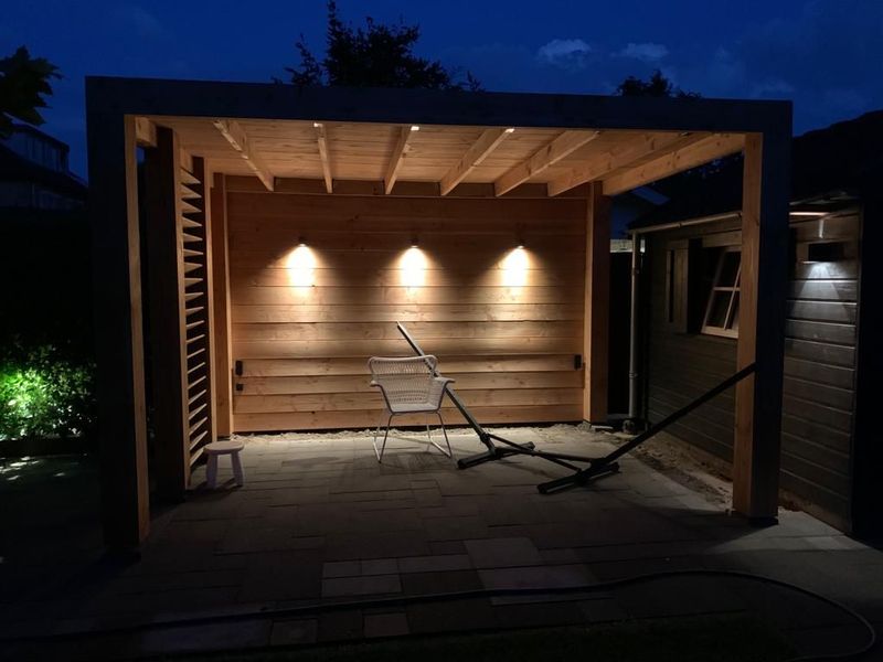 Houten overkapping in de tuin met sfeerverlichting