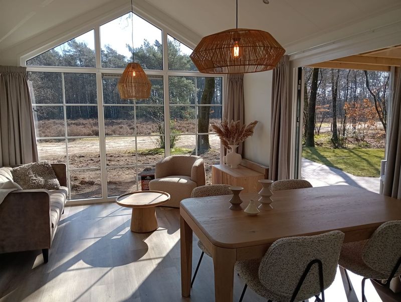 Lichte woonkamer met houten vloer en grote glazen pui